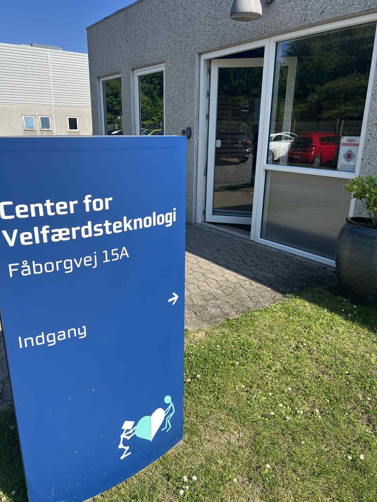 Viser skiltet til indgangen ved Center for Velfærdsteknologi, hvor døren står åbent indtil showroomet